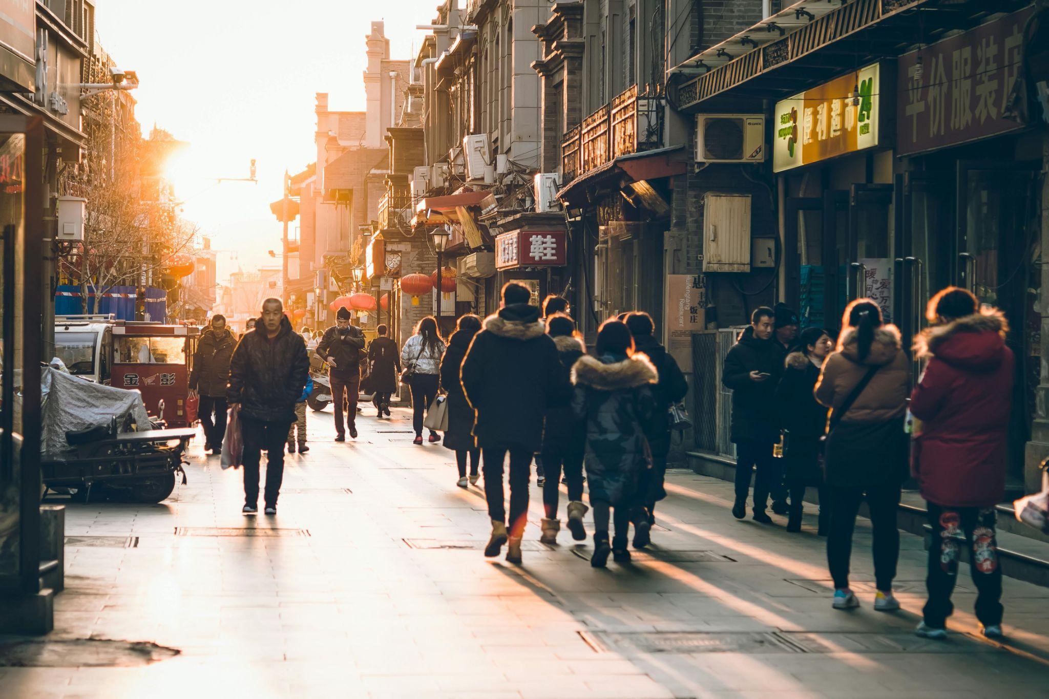 Street scene at sunset with people walking along an alley, conveying what it means to contend for the faith in modern times.