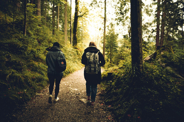 Two people walk through a sunlit forest path, symbolizing a faith journey.