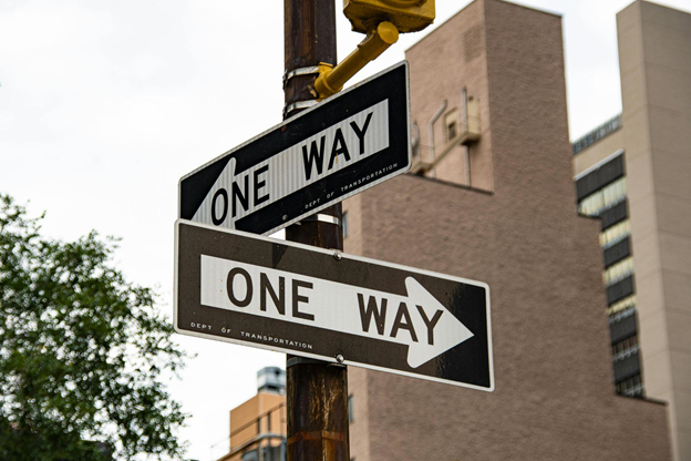 Two "One Way" street signs point in opposite directions on a single pole, 