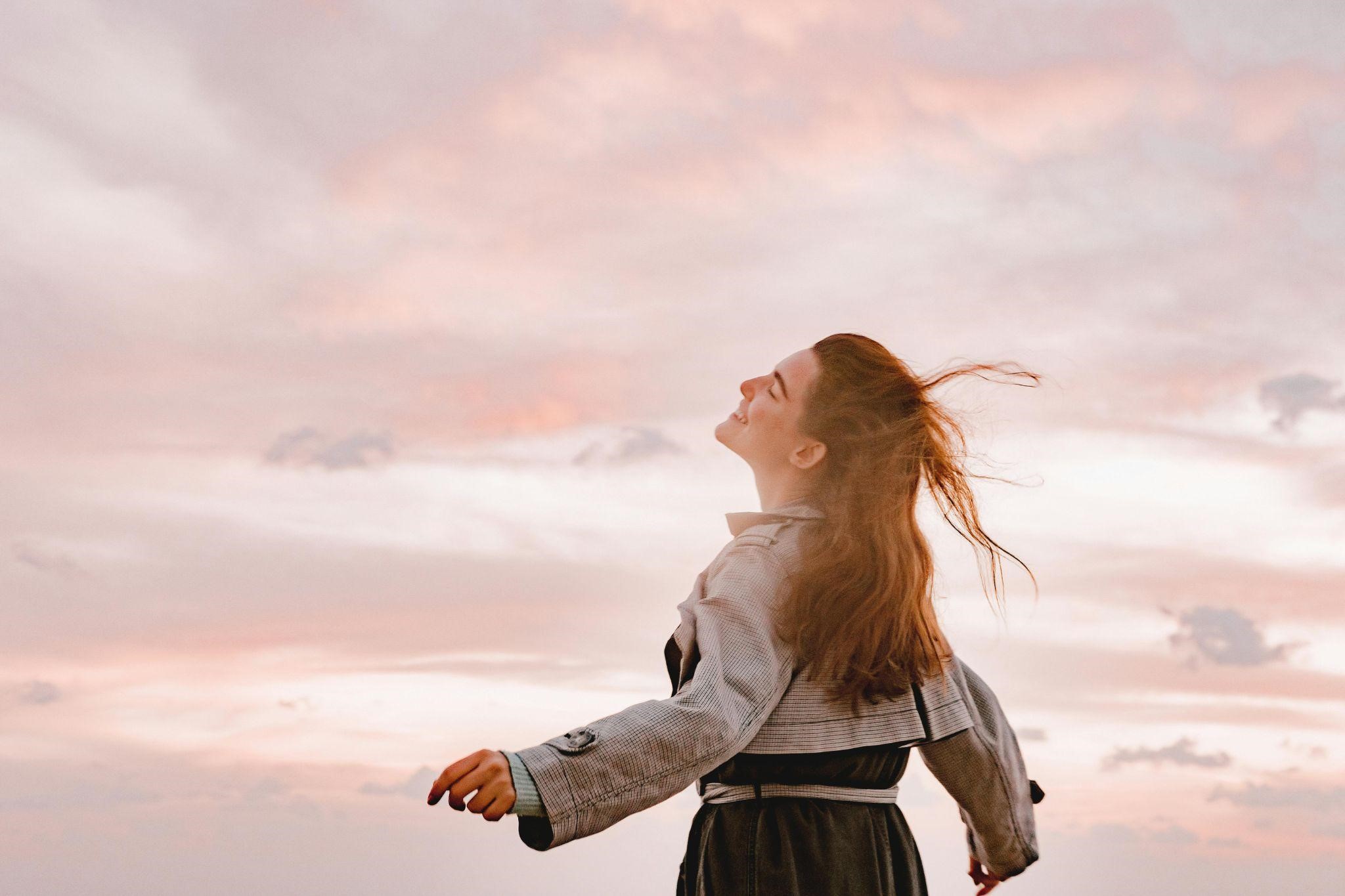 A person against a sky, smiling and tilting their head back, reflecting on the idea to let your faith be bigger than your fear.