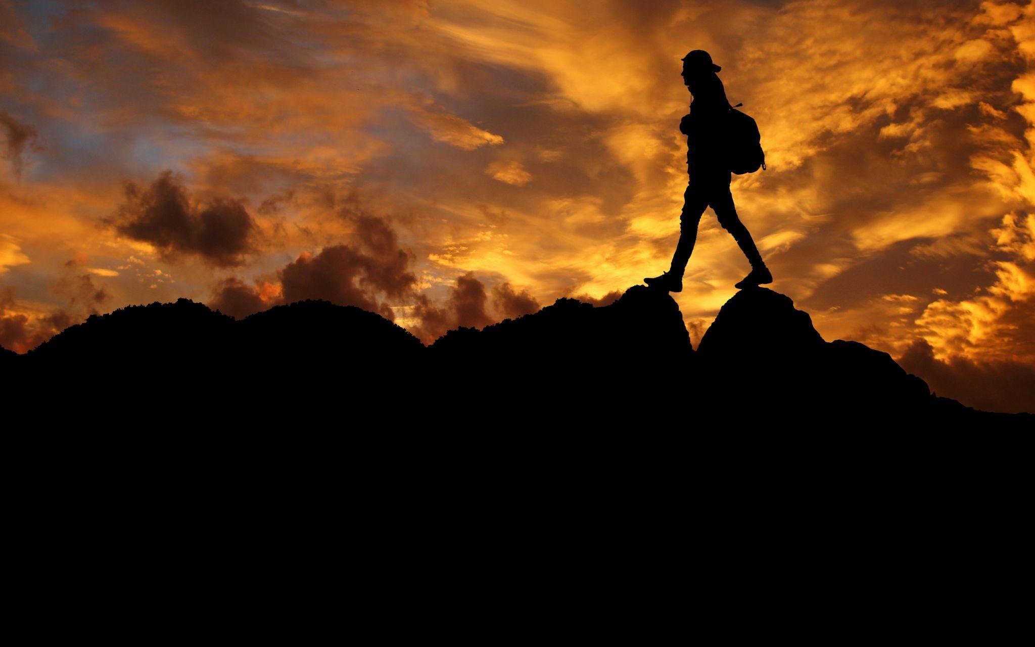 Silhouetted person walking on rocky terrain, symbolizing what gives people strength during trials.