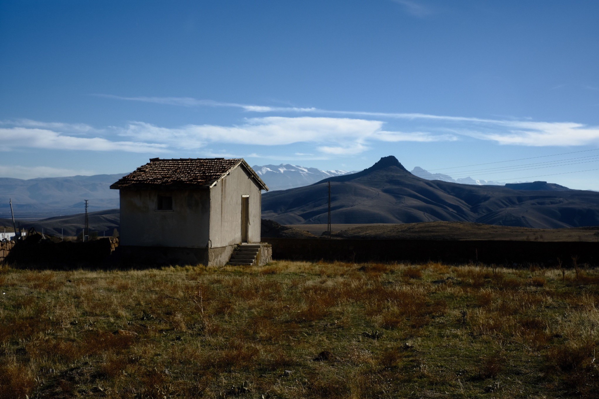 Jean Archambault- White_Month 6 banner A solitary house in an expansive field, illustrating the lifestyle of pioneer families on the frontier.